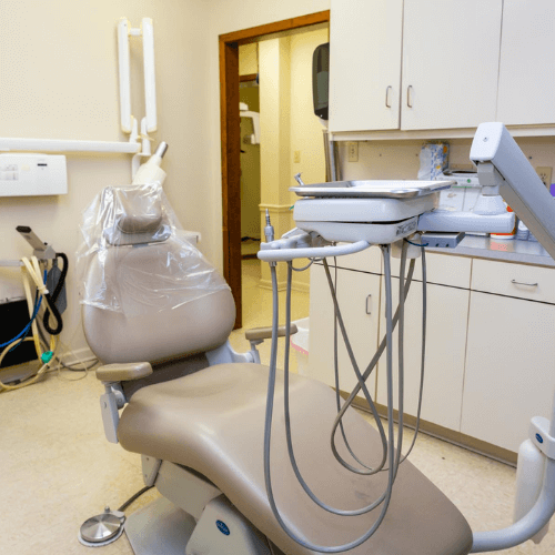 A dental exam room with a dental chair and cabinents.