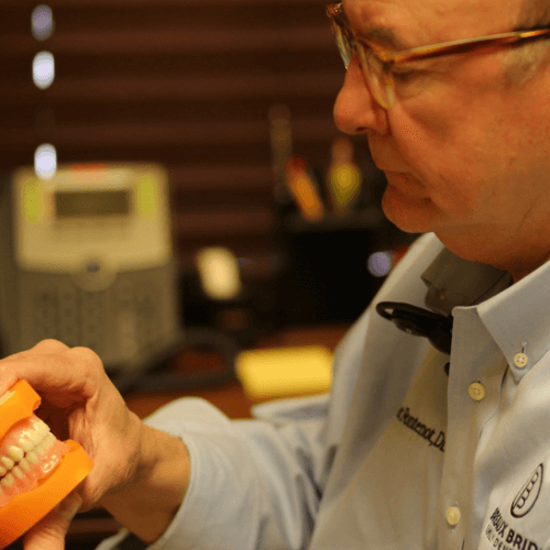 Dentist examining a full denture model during a consultation.