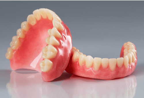 A set of dentures on a grey background.