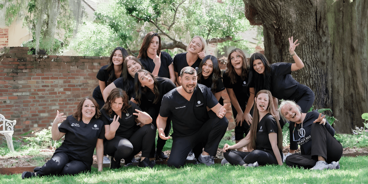 Dental practice team posing together outside in a fun, playful group photo.