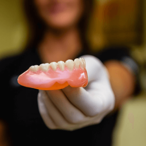 Close up of dentures being held by hygienist. 