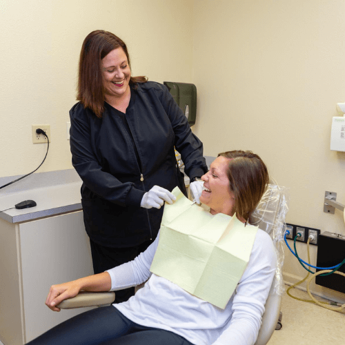 dental assistant putting on bib for client