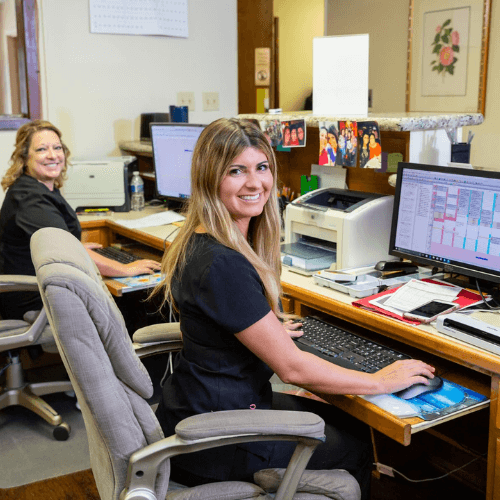 front desk staff smiling at camera while working at computers