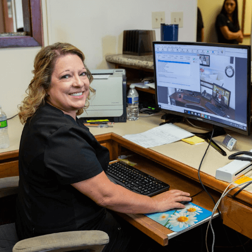 Front desk staff smiling at camera in front of computer